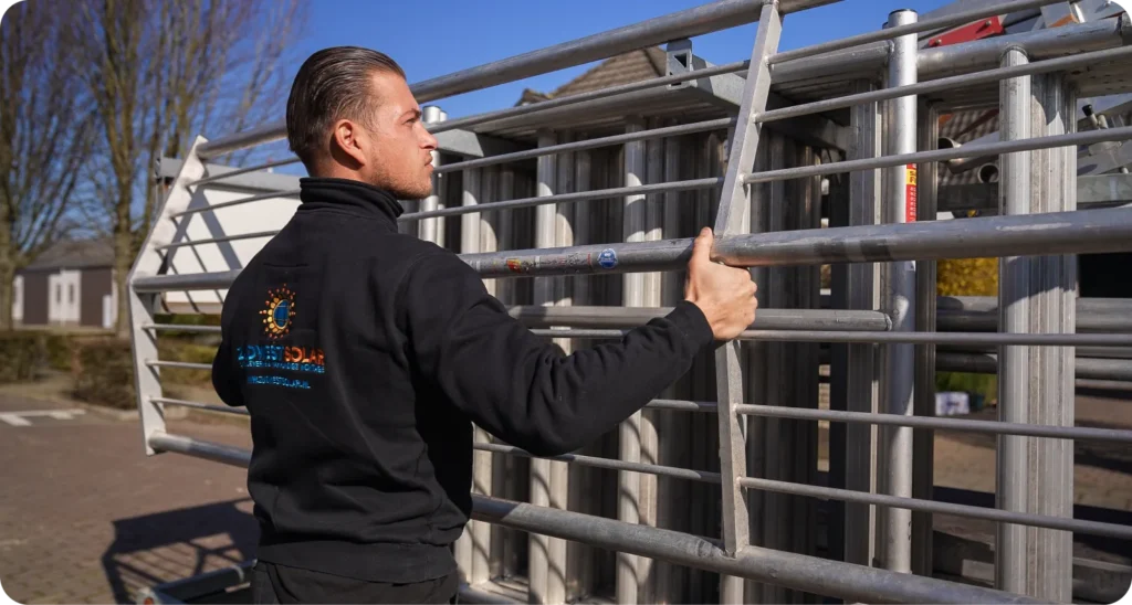 Monteur in ZuidWest Solar-trui zet een aluminium rolsteiger klaar bij een woning