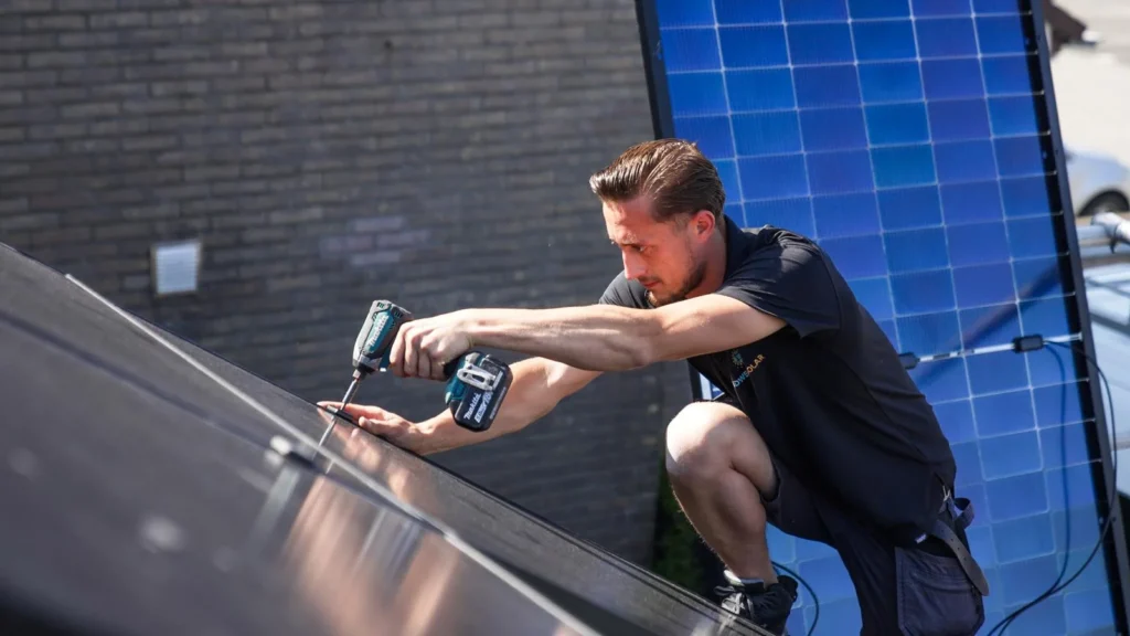 Monteur van ZuidWest Solar schroeft een zonnepaneel vast op een dak